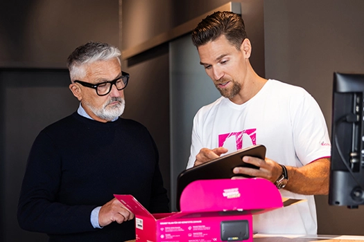 Zwei Männer besprechen Telekom Vertrag, Tablet und Router im Telekom Shop